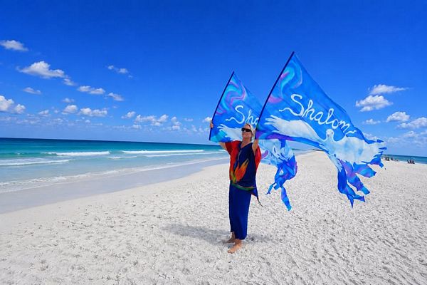 Lora holding her Shalom worship flags at the beach.
